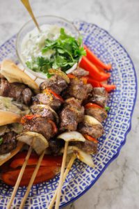 spicy lamb kebabs on skewers served in a plate with yogurt sauce